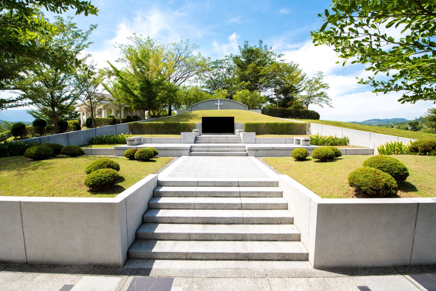 Landscaped Christian memorial garden with a white cross and burial terraces